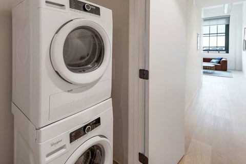 A stack of three white Whirlpool washing machines in a laundry room.